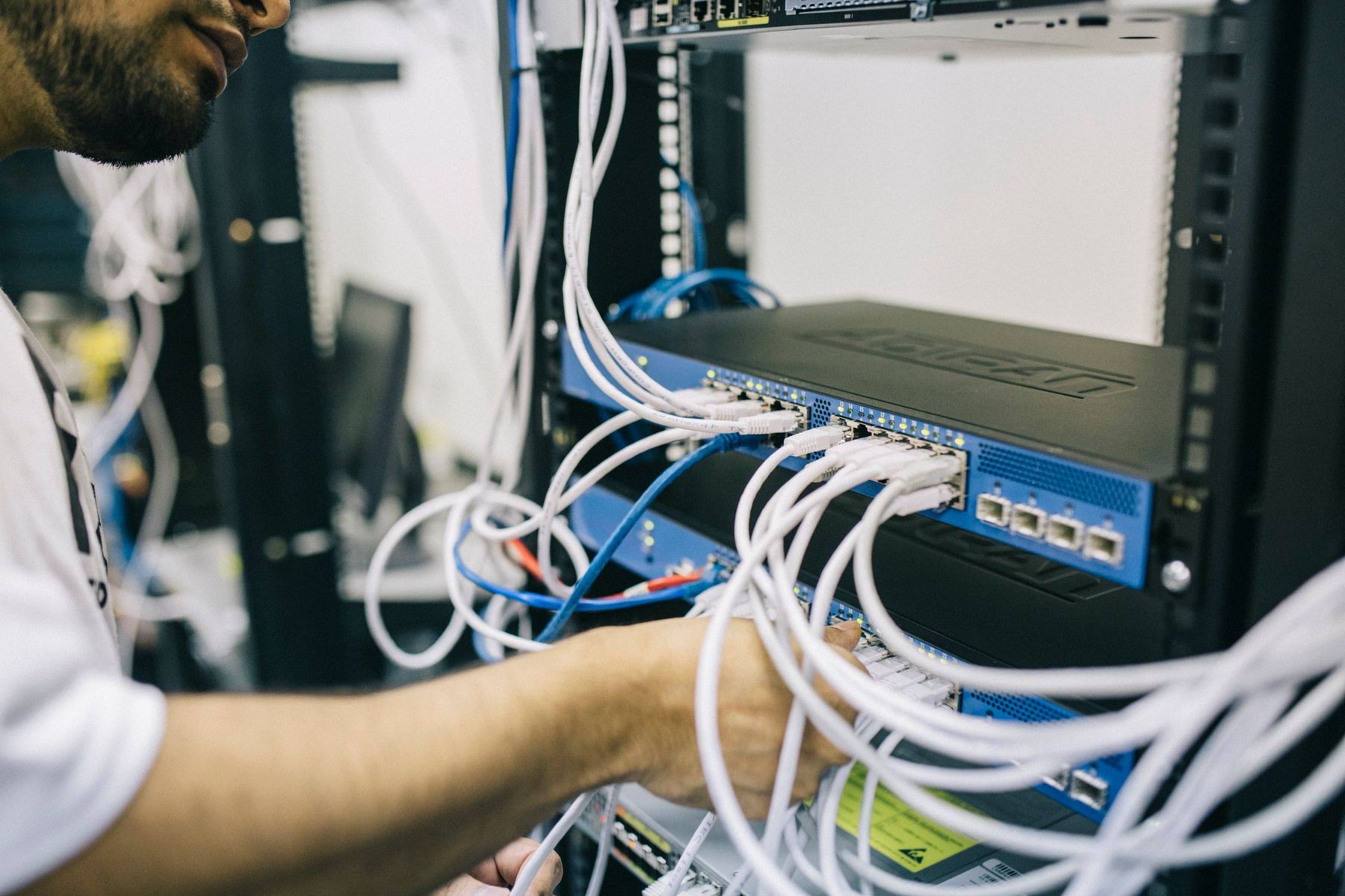 Técnico trabajando en el cableado y los equipos de una red empresarial